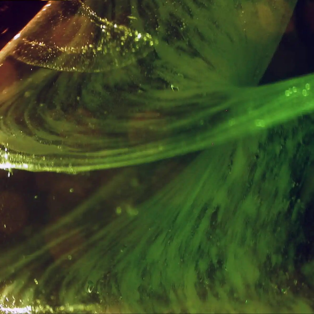 Wogende grüne Flüssigkeit im Glas.
